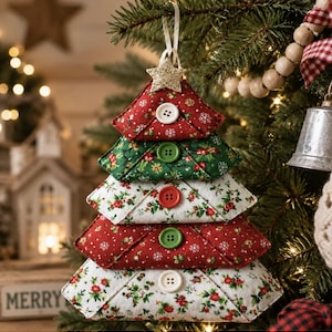 May include: A fabric Christmas tree ornament composed of five stacked triangular segments in red, green, and white floral patterns. Each segment features a single button at the center, and the top is adorned with a small, glittery gold star.