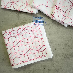 Può includere: Quadrati di tessuto bianco con ricami Sashiko rossi in motivi geometrici. Il testo Sashiko Patterns made simple è stampato in blu. I pezzi di tessuto sono disposti in un gruppo, mostrando gli intricati disegni cuciti in rosso su bianco.