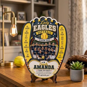 May include: A wooden softball glove-shaped plaque featuring the text Lady Eagles Softball Season 2026, a team photo, player names and numbers, and the text Coach Amanda Thank You Coach for believing in us, pushing us, and inspiring us to be our best.