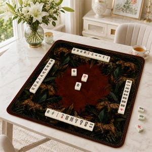 May include: A square mahjong mat featuring a dark red centre surrounded by a border of tigers and tropical foliage. Four rows of white mahjong tiles are arranged along the edges, with three additional tiles placed in the centre of the mat.