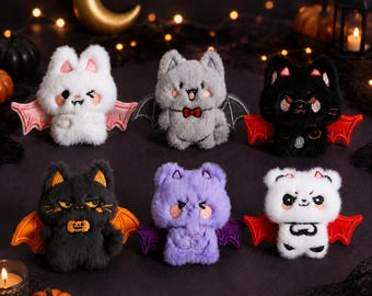 May include: Six small plush bat toys with embroidered facial features and wings. The collection includes a white bat with pink wings, a grey bat with a bow tie, a black bat with red wings, a black bat with orange wings, a purple bat, and a white bat.