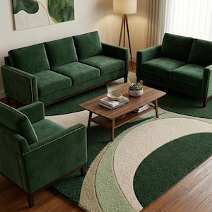 May include: A living room set featuring a three-seat sofa, a two-seat loveseat, and an armchair, all upholstered in dark green velvet with gold nailhead trim. A rectangular wooden coffee table sits on a green and cream patterned area rug.