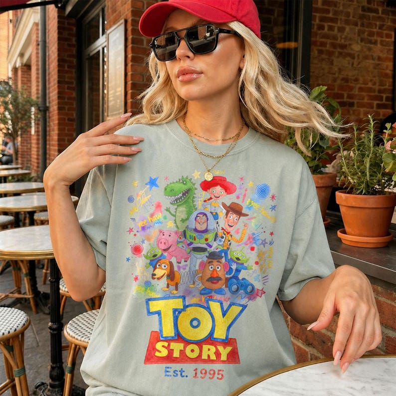 以下が含まれることがあります： アニメ映画のキャラクターが描かれた、明るい緑色のトイ・ストーリーTシャツ。Tシャツにはトイ・ストーリーのロゴと「Est. 1995」の文字がプリントされています。Tシャツは柔らかい素材で作られています。
