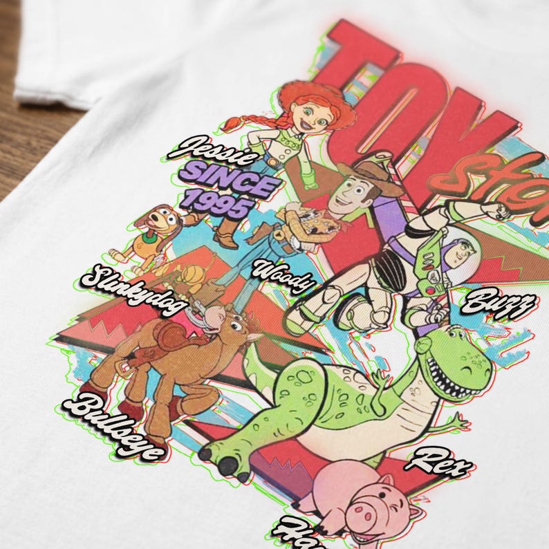May include: A white t-shirt featuring a colorful graphic of Toy Story characters including Jessie, Woody, Buzz Lightyear, Slinky Dog, Bullseye, Rex, and Hamm. The design includes the text "Toy Story", "Jessie SINCE 1995", and individual character names.
