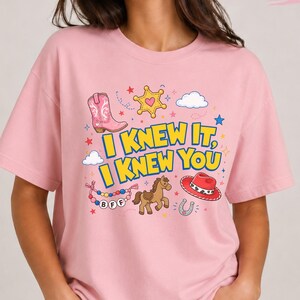 Oversized tee with “I Knew It, I Knew You” western graphic, pink boot, cowboy hat, horse, sheriff star, clouds, stars, and BFF beads.