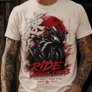 May include: A beige short-sleeve t-shirt featuring a graphic of a black sport motorcycle centred over a red circular brushstroke. The design includes Japanese characters, the text "RIDE WITHOUT LIMITS," and "LIVE FAST • RIDE FREE."