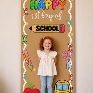 Peut inclure: Une bannière verticale en tissu beige avec le texte HAPPY 1st day of SCHOOL et des illustrations scolaires colorées, notamment un crayon jaune, un crayon rose, des ciseaux, une pomme rouge et un bus scolaire jaune avec des confettis.