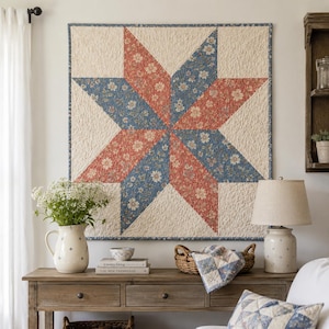 May include: A large, quilted wall hanging featuring a star design. The star is composed of alternating red and blue floral print triangles set against a cream-colored background. The quilt is mounted on a white wall, creating a focal point in a cozy living space.