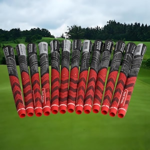Könnte beinhalten: Eine Sammlung roter und schwarzer Golfschlägergriffe. Die Griffe haben ein strukturiertes Muster, und der Text "Golf Pride" ist auf einigen sichtbar. Der Hintergrund zeigt einen grünen Golfplatz und einen bewölkten Himmel.