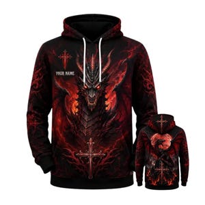 May include: A black hooded sweatshirt featuring a large, detailed graphic of a dragon with glowing red eyes and wings. The design includes red lightning patterns, two ornate crosses, and the text YOUR NAME printed on the front chest area.