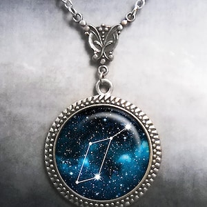 May include: A silver necklace with a round pendant featuring a constellation against a blue and black galaxy background.
