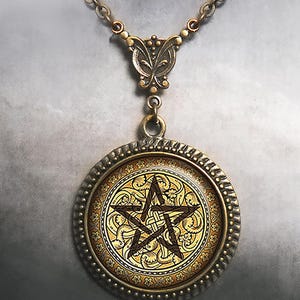 May include: A round pendant necklace featuring an antique bronze-toned metal frame with a textured edge. The center displays a dark brown pentagram symbol set against a gold-colored background with intricate, swirling floral and vine patterns.