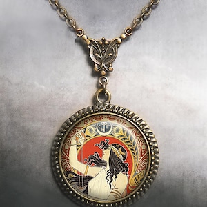 May include: A bronze necklace with a round pendant featuring a vintage illustration of a woman with long dark hair holding a lyre. The pendant has a decorative border and the text "C.T." in the center.