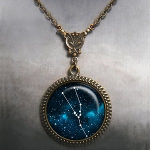May include: A bronze necklace with a round pendant featuring a depiction of the Taurus constellation against a dark blue starry sky background.