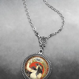 May include: A silver chain necklace with a round pendant featuring a vintage art nouveau illustration of a woman with long dark hair holding a lyre. The pendant has a silver border with a decorative pattern.