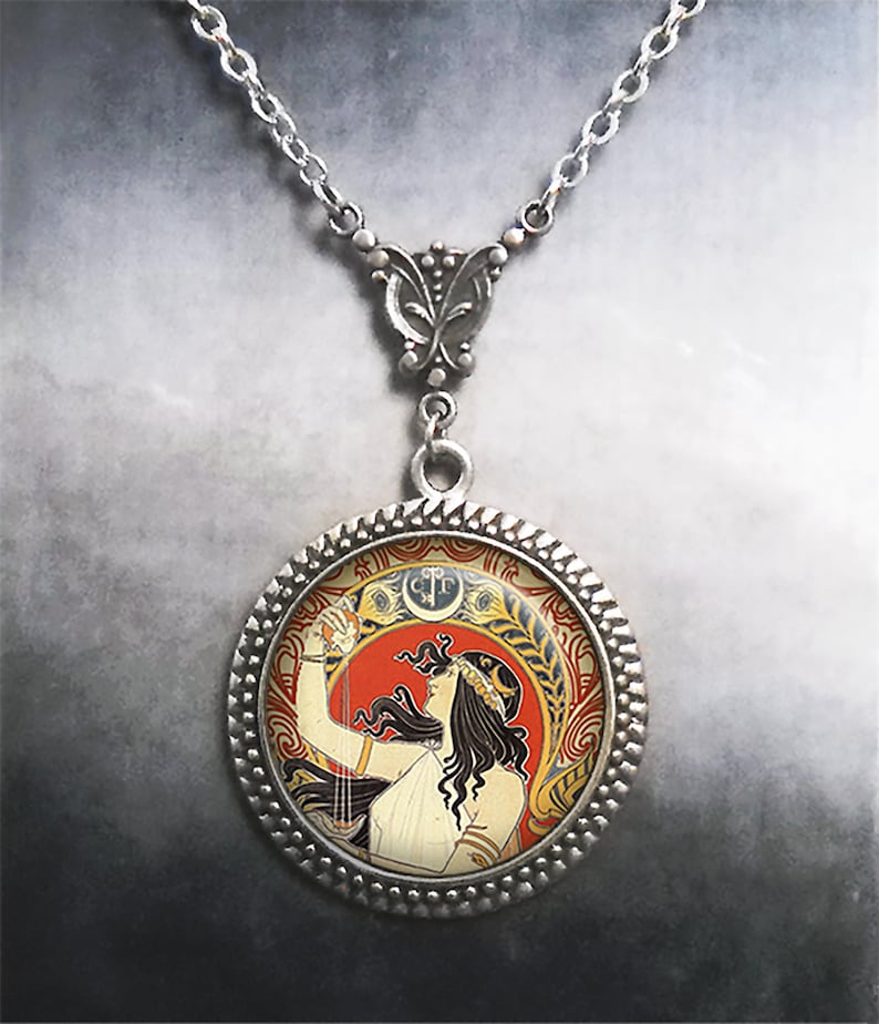 May include: A silver necklace with a round pendant featuring a vintage illustration of a woman in a white dress holding a glass of wine. The pendant has a decorative silver border.