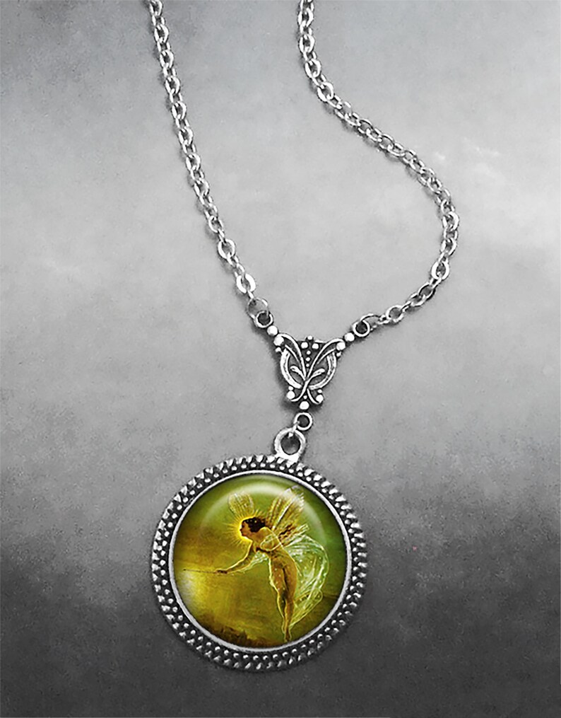 May include: A silver necklace with a round pendant featuring a painting of a fairy with wings, holding a glowing orb. The pendant has a silver filigree border and a silver butterfly charm.