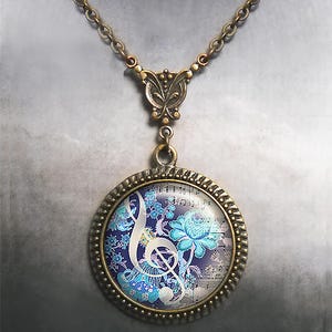 May include: A bronze necklace with a round pendant featuring a treble clef surrounded by blue and white floral designs on a musical sheet background.