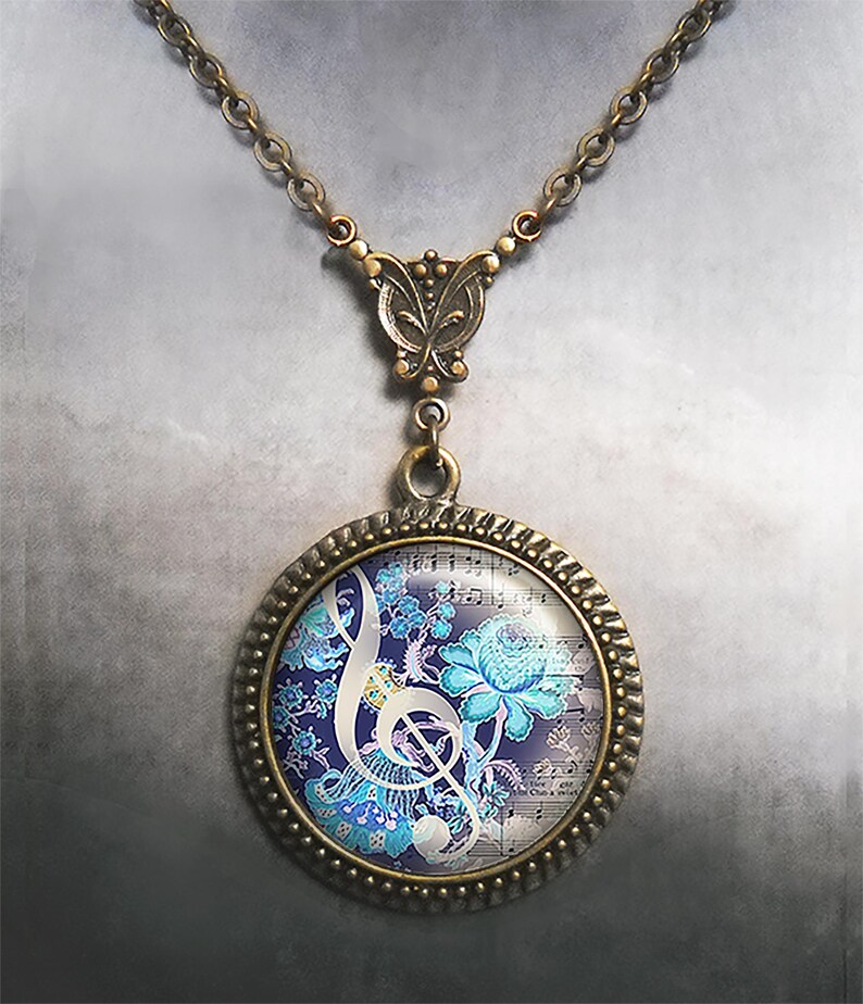 May include: A bronze necklace with a round pendant featuring a treble clef surrounded by blue and white floral designs on a musical sheet background.