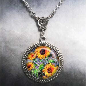 May include: A silver necklace with a round pendant featuring a painting of sunflowers. The pendant has a detailed silver frame.