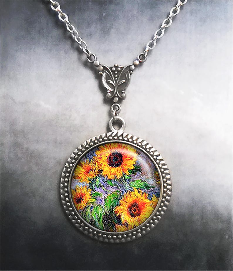 May include: A silver necklace with a round pendant featuring a painting of sunflowers. The pendant has a detailed silver frame.