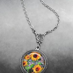 May include: A silver chain necklace with a round pendant featuring a painting of sunflowers. The pendant has a silver filigree design around the edge.