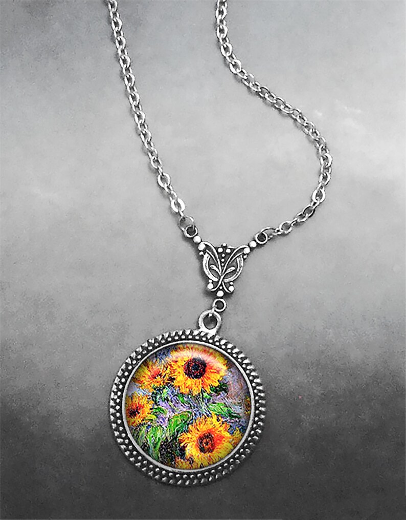 May include: A silver chain necklace with a round pendant featuring a painting of sunflowers. The pendant has a silver filigree design around the edge.