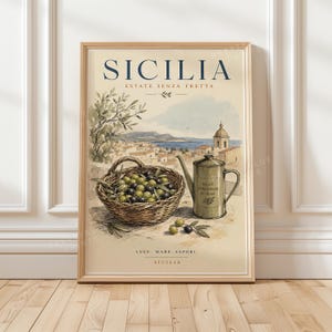Può includere: Una stampa d'arte incorniciata intitolata SICILIA ESTATE SENZA FRETTA con un cesto di vimini pieno di olive verdi e nere, una brocca per olio d'oliva in metallo e un paesaggio costiero. Il testo recita SICILIA, ESTATE SENZA FRETTA, LUCE, MARE, SAPORI.