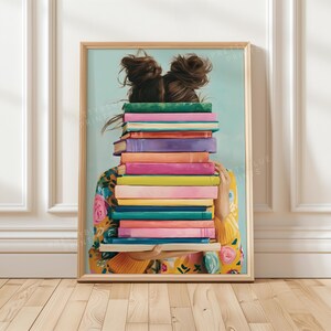 Peut inclure: Une impression d'art encadrée représentant une personne aux cheveux bruns coiffés en deux chignons, tenant une haute pile de livres colorés qui cachent son visage. Elle porte un pull jaune à motifs floraux sur un fond bleu clair.