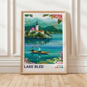 Può includere: Una stampa artistica incorniciata con un'illustrazione panoramica del lago di Bled, in Slovenia. L'opera raffigura un lago con una piccola barca, una chiesa e montagne sullo sfondo. Il testo "LAKE BLED" è in basso.