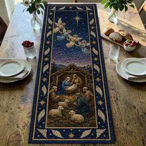 Op de afbeelding: Een rechthoekige, doorgestikte tafelloper met een donkerblauwe kerststalscène met een kribbe, figuren, schapen en engelen onder een sterrenhemel. De rand is versierd met goudkleurige engelvleugels en sterren op een donkerblauwe achtergrond.