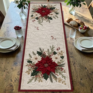 May include: A rectangular table runner featuring a cream-colored fabric with an intricate quilted swirl pattern. The runner is decorated with two large floral arrangements of red and white poinsettias, green pine needles, pinecones, and red berries.