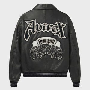 May include: Black leather jacket with a classic bomber style. Features the brand name "Avirex" in large white lettering on the back, along with "New York" and two lion emblems. The jacket has a ribbed hem and cuffs.