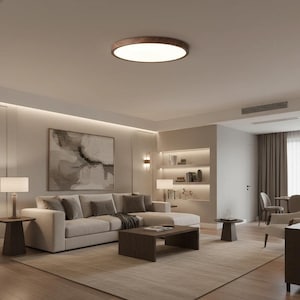 Puede incluir: Un salón moderno con una paleta de colores neutros. Un gran sofá seccional de color claro se encuentra sobre una alfombra beige. También se ven una mesa de centro de madera oscura y una lámpara de techo redonda con moldura de madera.