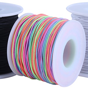 May include: Three spools of elastic cord, one black, one white, and one with a rainbow of colors.