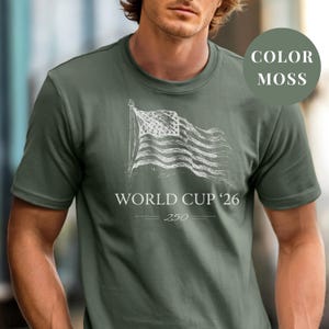Moss Comfort Colors 1717 t-shirt featuring a minimalist vintage sketch of a waving American flag. Includes "WORLD CUP '26" and a stylized "250" text celebrating the USA Semiquincentennial. Premium patriotic sports apparel for United States soccer fans and 2026 host nation supporters.