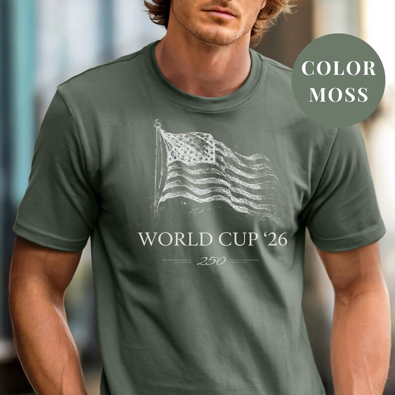 Moss Comfort Colors 1717 t-shirt featuring a minimalist vintage sketch of a waving American flag. Includes "WORLD CUP '26" and a stylized "250" text celebrating the USA Semiquincentennial. Premium patriotic sports apparel for United States soccer fans and 2026 host nation supporters.