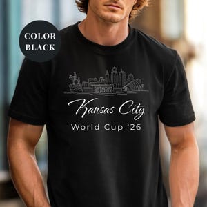 Black Comfort Colors T-shirt featuring a minimalist white line art Kansas City skyline design, elegant Kansas City script lettering, and World Cup ’26 text, styled as a soccer travel souvenir shirt for Kansas City fans, football lovers, and 2026 World Cup city apparel.
