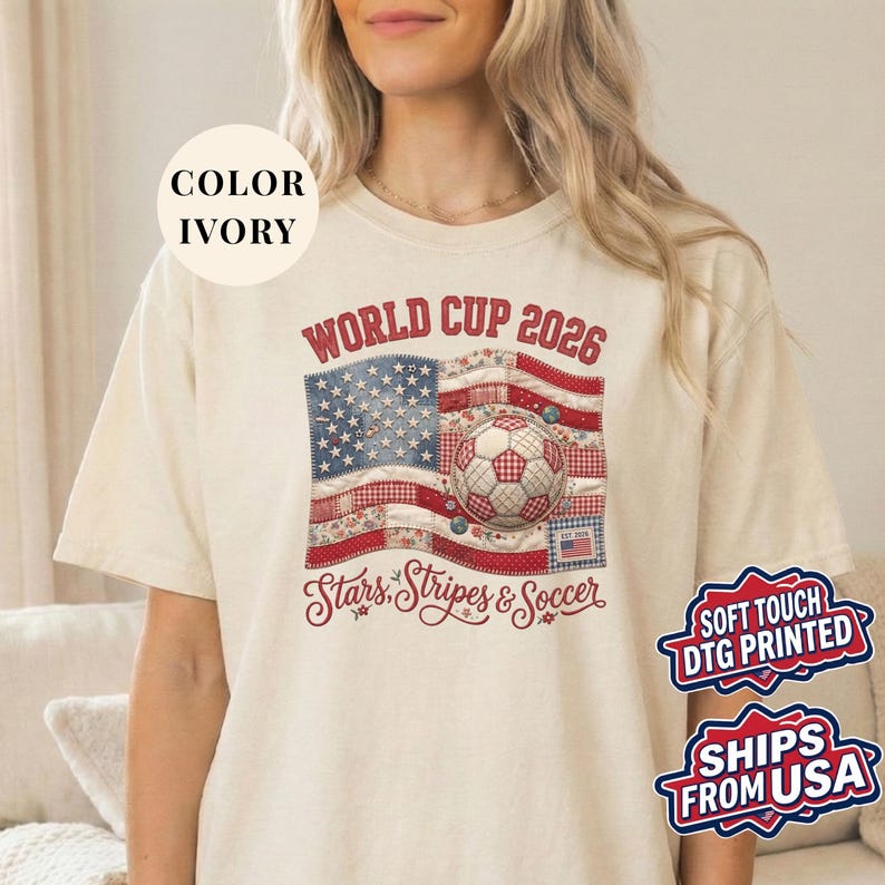Ivory colored t-shirt featuring a vintage patchwork American flag design for World Cup 2026. The faux quilted graphic includes floral and gingham fabric textures, a stitched soccer ball, and "Stars, Stripes & Soccer" text. Unique patriotic sports apparel for women and USA soccer fans.
