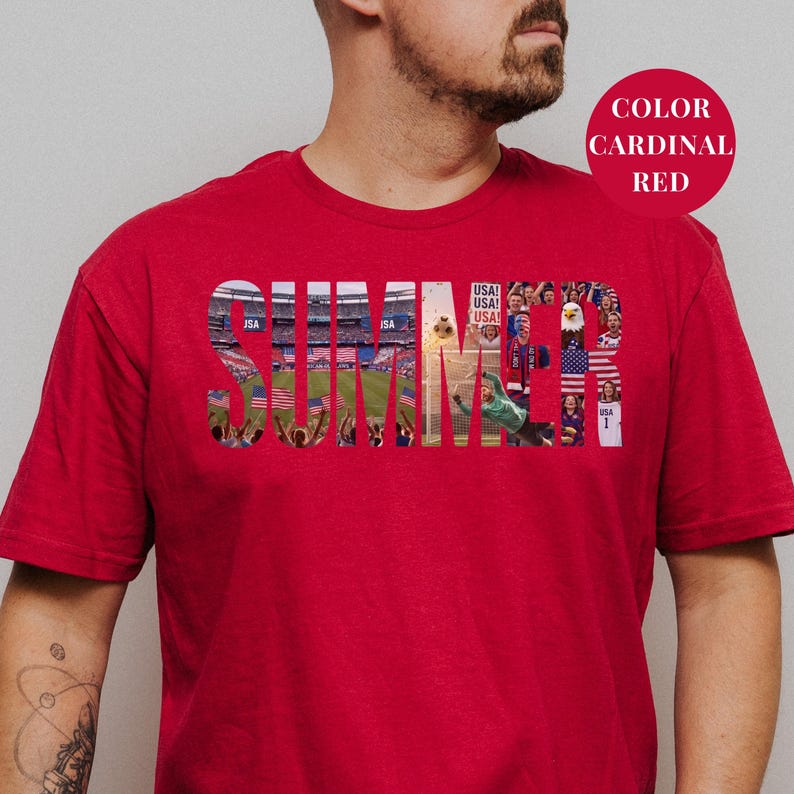 Red Gildan t-shirt featuring a "SUMMER" photo collage graphic. The bold block letters are filled with USA soccer scenes, including a packed stadium, American flags, cheering fans, and a diving goalie. Patriotic sports apparel for World Cup 2026 supporters.