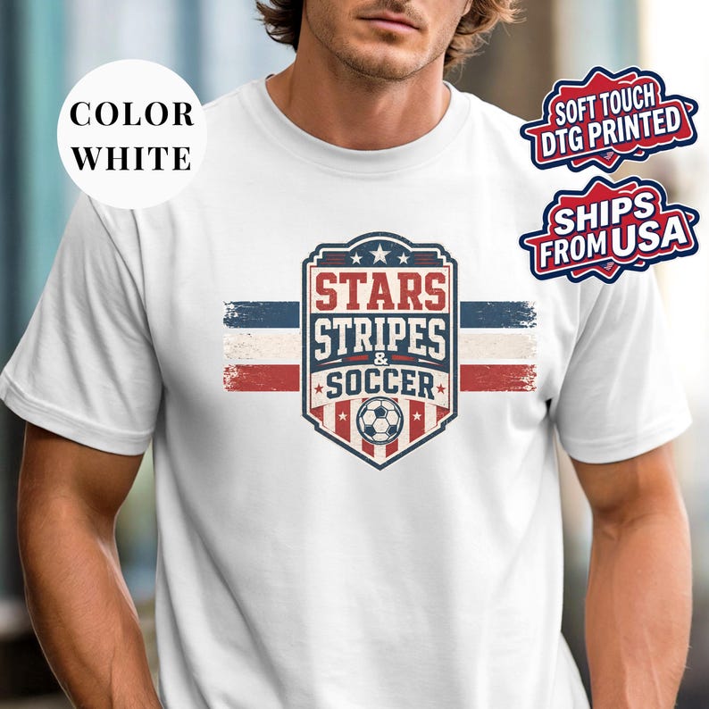 A man wearing a white t-shirt with a graphic design featuring a shield-shaped logo with the text "STARS & SOCCER" and a soccer ball.