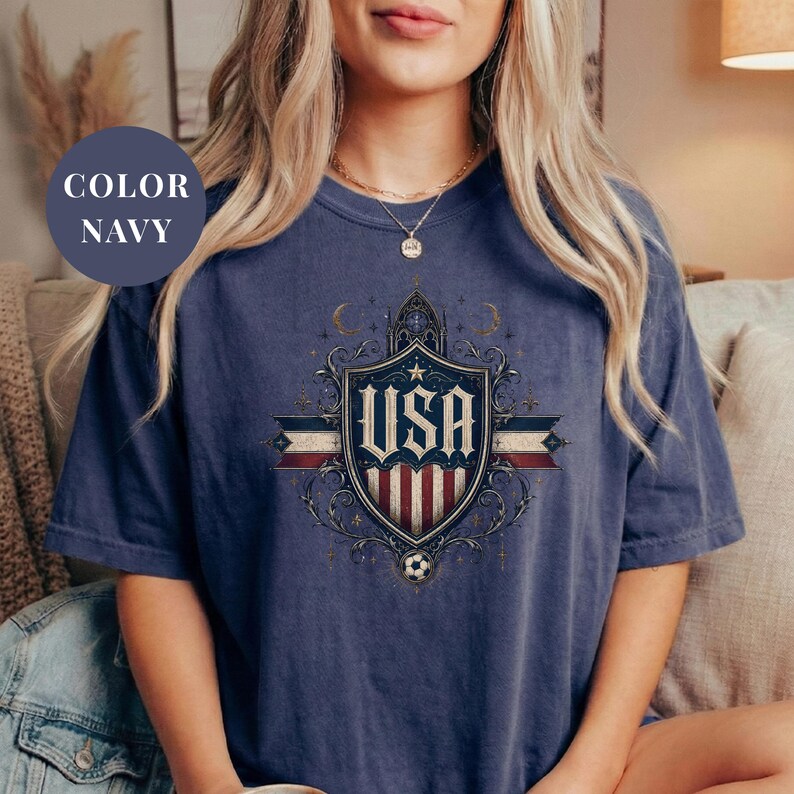 A woman wearing a navy blue t-shirt with a graphic design of the United States flag and the word "USA" printed on it.