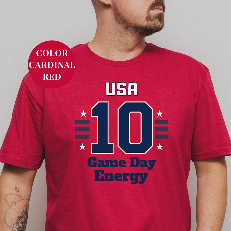 A man wearing a red t-shirt with the text "USA 10 Game Day Energy" printed on it.