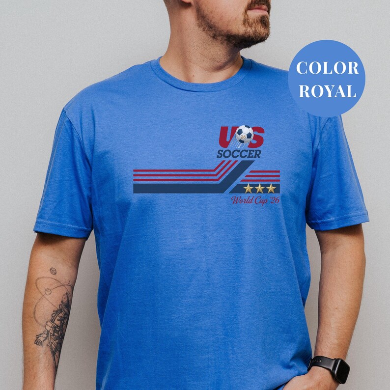 A man wearing a blue t-shirt with a graphic design featuring a soccer ball and the text "US SOCCER World Cup 26".