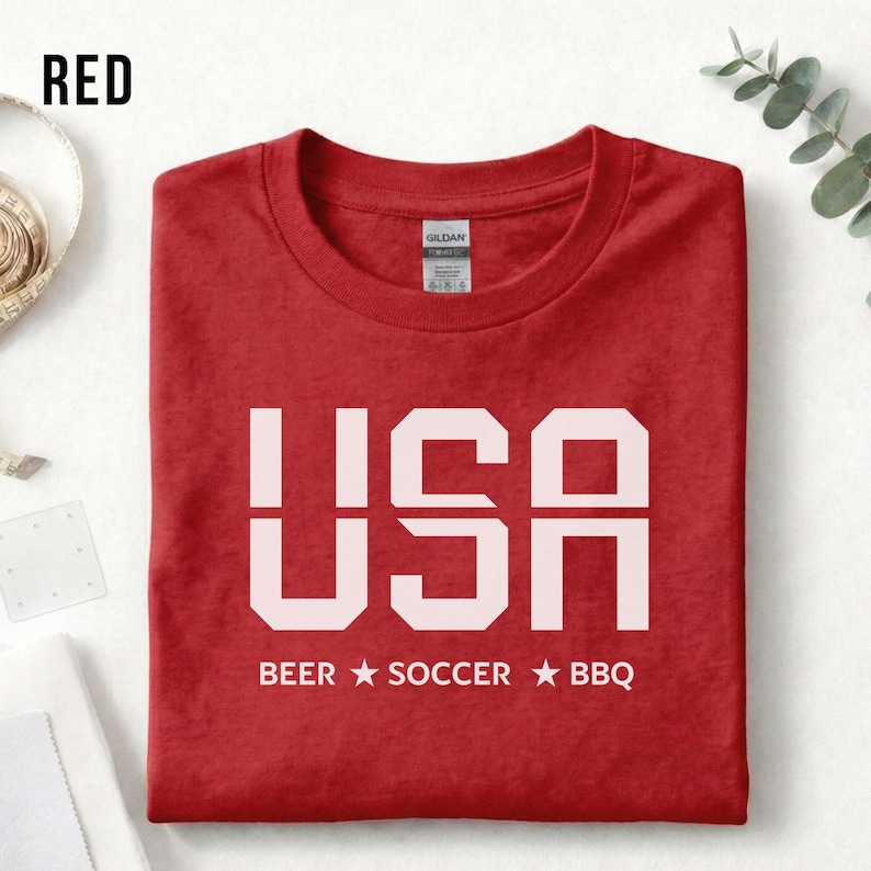 Red USA T-shirt for Soccer Fans featuring bold block letters and ‘Beer Soccer BBQ’ slogan, patriotic graphic tee for World Cup 2026 and game day wear.