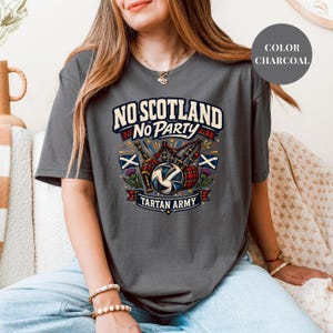 A woman wearing a grey t-shirt with a graphic design that says "NO SCOTLAND NO PARTY TARTAN ARMY".