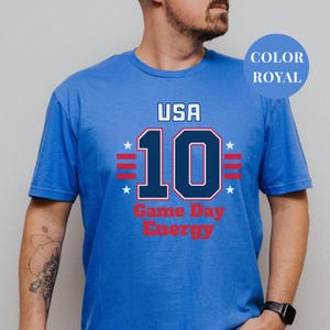 A man wearing a blue t-shirt with the text "USA 10 Game Day Energy" printed on it.