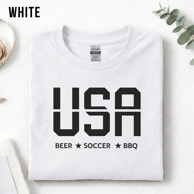 White USA T-shirt for Soccer Fans featuring bold block letters and ‘Beer Soccer BBQ’ slogan, patriotic graphic tee for World Cup 2026 and game day wear.