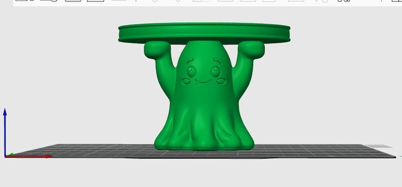 Pu&ograve; includere: Un modello 3D verde brillante di un piccolo supporto con una figura centrale a forma di fantasma con le braccia sollevate che sostengono un piano circolare piatto. Il fantasma ha un volto sorridente con grandi occhi e guance rosate, reso digitalmente.