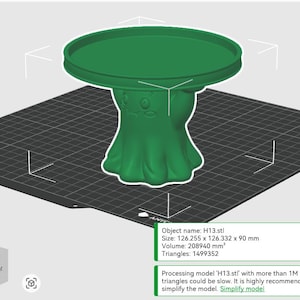 Pu&ograve; includere: Un modello 3D verde di un supporto a piedistallo con piano circolare e una base che presenta un volto stilizzato. L'interfaccia software mostra il nome dell'oggetto H13.stl, dimensioni di 126,255 x 126,332 x 90 mm, un volume di 208940 mm3 e 1499352 triangoli.